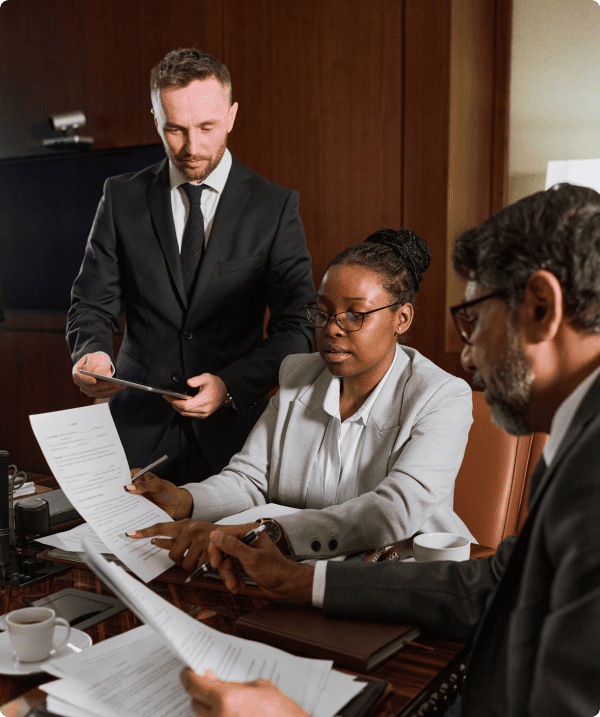 Three professionals reviewing documents at conference table