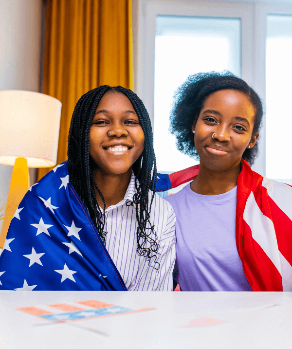 Two smiling girls wrapped in American flags